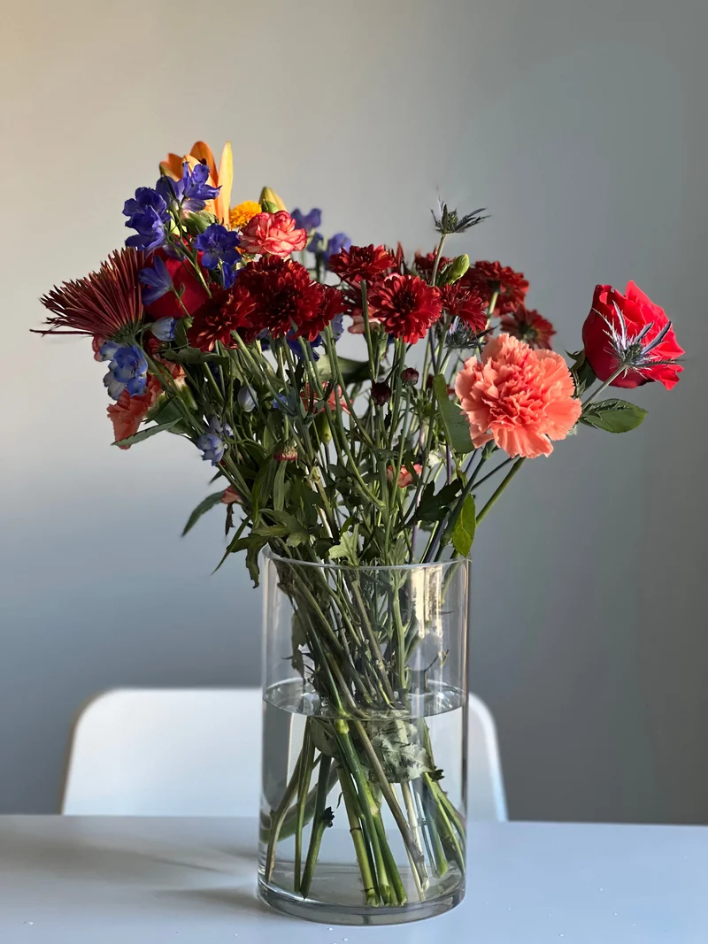 A phone photo of mixed flowers in a glass vase