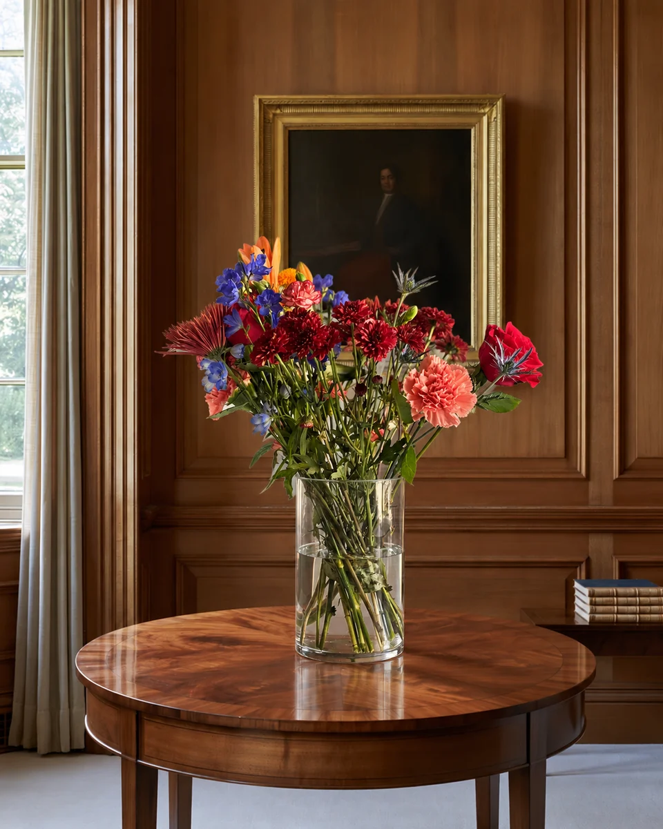 Illustrative test example: Mixed arrangement in a glass vase on a round mahogany table in a wood-panelled room