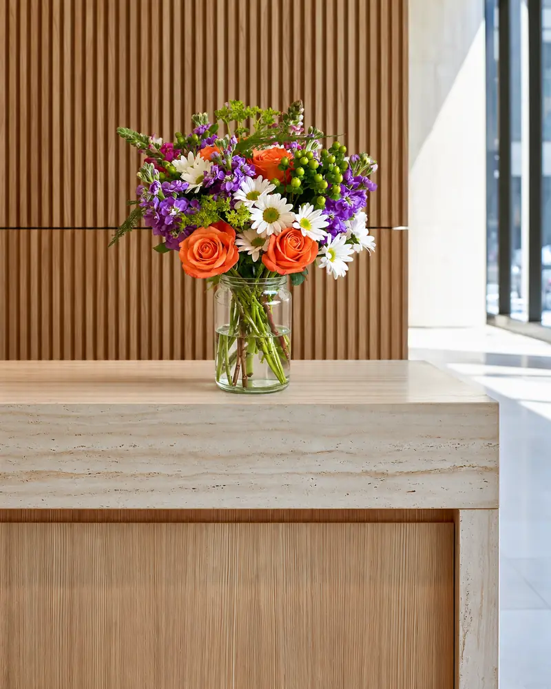 Example with sample flowers: a vase arrangement in the Reception desk · travertine room, kept as made